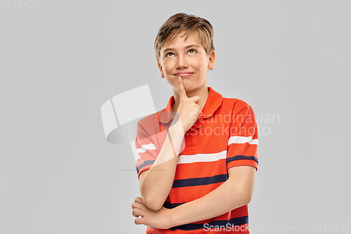 Image of portrait of happy thinking boy in red polo t-shirt