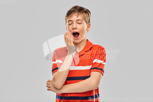 Image of portrait of tired yawning boy in red polo t-shirt