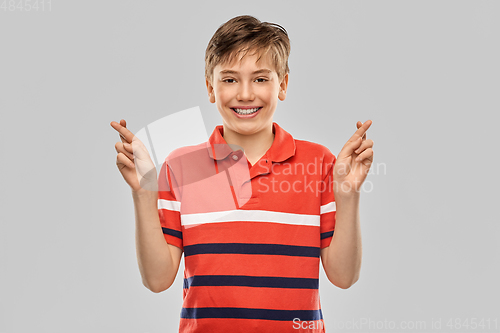 Image of smiling boy in t-shirt holding fingers crossed