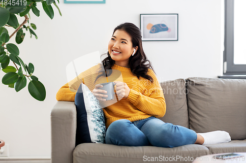 Image of woman in earphones listening to music at home