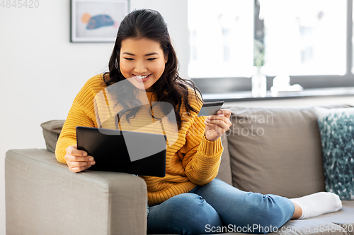 Image of asian woman with tablet pc and credit card at home