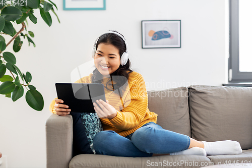 Image of asian woman with headphones and tablet pc at home