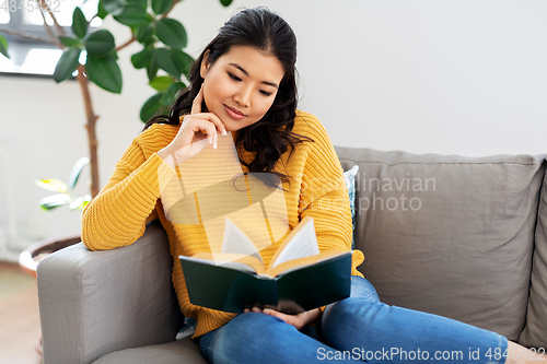 Image of asian young woman reading book at home