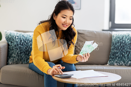 Image of woman with money, papers and calculator at home