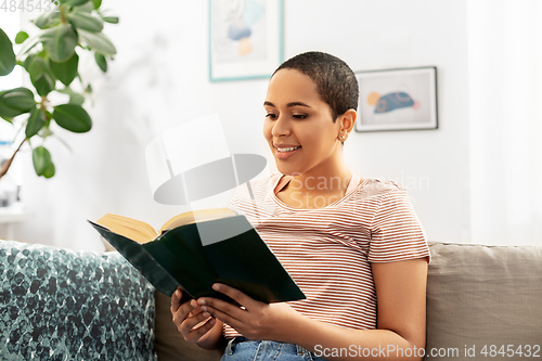 Image of happy african american woman reading book at home