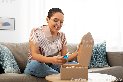 Image of african american woman opening parcel box at home