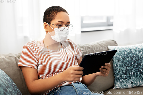 Image of woman in medical mask with tablet pc at home