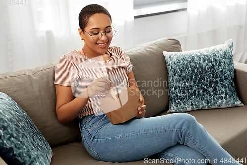 Image of african woman eating food with chopsticks at home