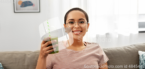 Image of african american woman drinking smoothie at home