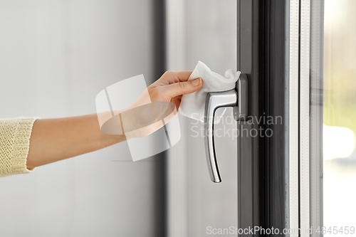 Image of woman cleaning window handle with wet wipe