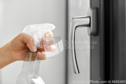 Image of hands cleaning window handle with detergent