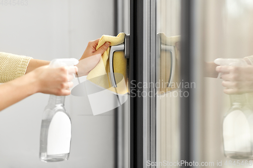 Image of hands cleaning window handle with detergent