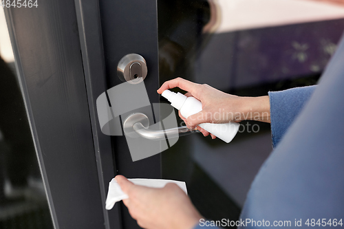 Image of hand cleaning door handle with disinfectant spray