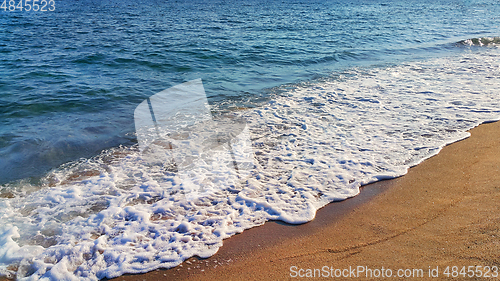 Image of Sea wave with white foam on the coastal sand