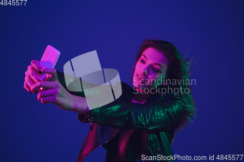 Image of Caucasian woman\'s portrait isolated on blue studio background in neon light