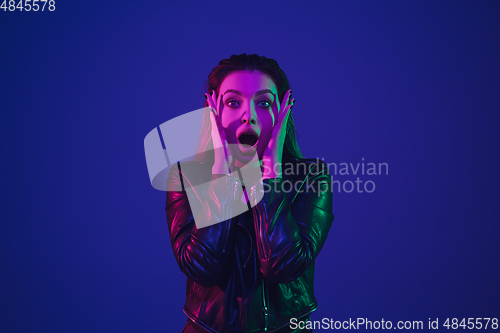 Image of Caucasian woman\'s portrait isolated on blue studio background in neon light