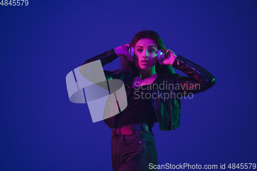 Image of Caucasian woman\'s portrait isolated on blue studio background in neon light