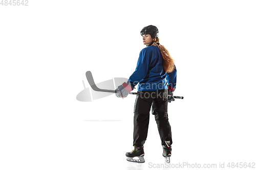 Image of Young female hockey player with the stick on ice court and white background