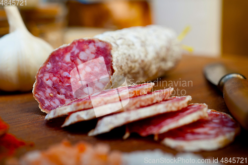 Image of traditional Italian salame cured sausage sliced on a wood board