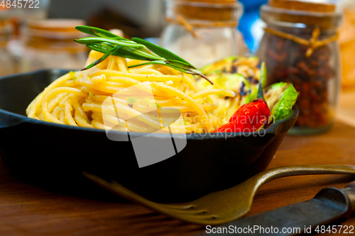 Image of italian spaghetti pasta with zucchini sauce on iron skillet