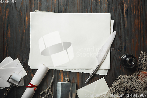 Image of Old fashioned flat lay with letters writing accessories on dark wooden background