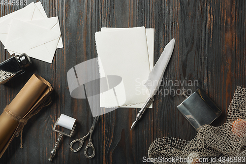 Image of Old fashioned flat lay with letters writing accessories on dark wooden background