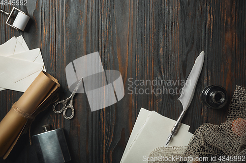 Image of Old fashioned flat lay with letters writing accessories on dark wooden background