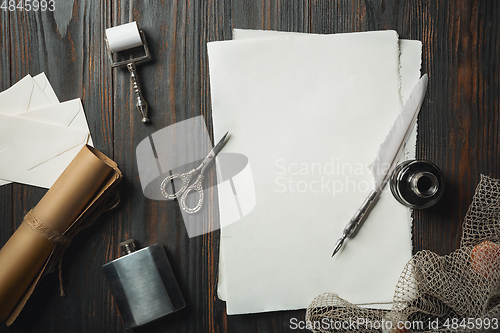 Image of Old fashioned flat lay with letters writing accessories on dark wooden background