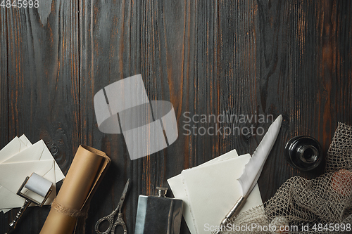 Image of Old fashioned flat lay with letters writing accessories on dark wooden background