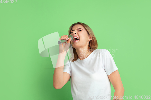 Image of Caucasian young woman\'s portrait on green studio background