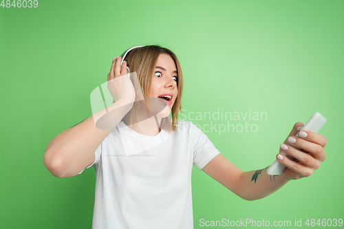 Image of Caucasian young woman\'s portrait on green studio background