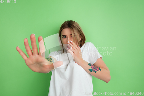 Image of Caucasian young woman\'s portrait on green studio background