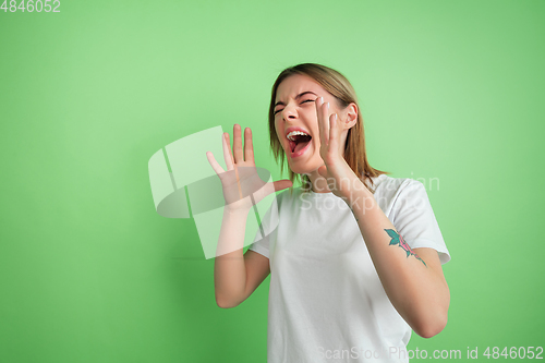 Image of Caucasian young woman\'s portrait on green studio background
