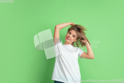 Image of Caucasian young woman\'s portrait on green studio background