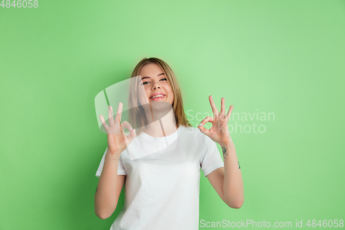 Image of Caucasian young woman\'s portrait on green studio background