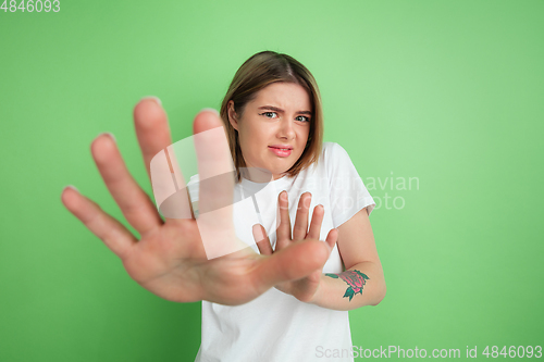 Image of Caucasian young woman\'s portrait on green studio background