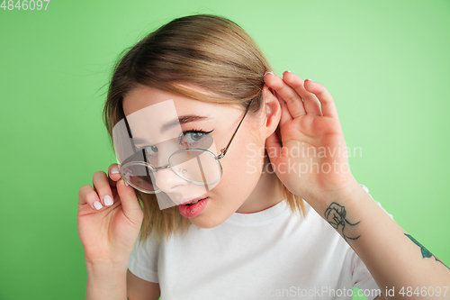 Image of Caucasian young woman\'s portrait on green studio background