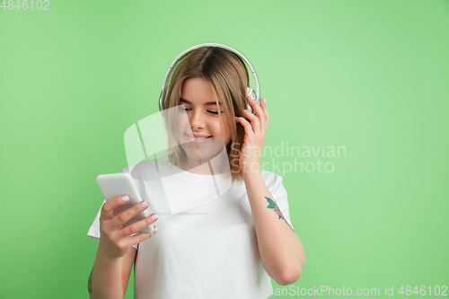 Image of Caucasian young woman\'s portrait on green studio background