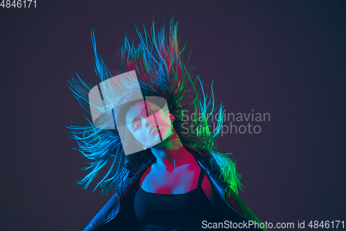 Image of Beautiful woman\'s portrait with blowing hair on dark studio background in colorful neon light