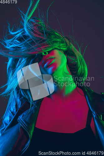 Image of Beautiful woman\'s portrait with blowing hair on dark studio background in colorful neon light