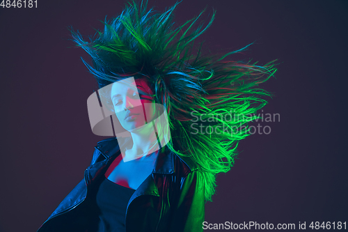 Image of Beautiful woman\'s portrait with blowing hair on dark studio background in colorful neon light