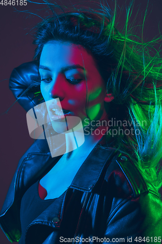 Image of Beautiful woman\'s portrait with blowing hair on dark studio background in colorful neon light
