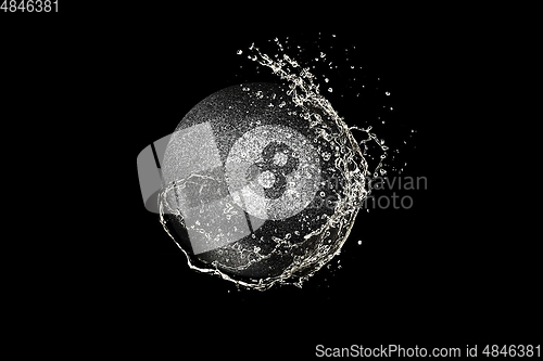 Image of Billiards ball flying in water drops and splashes isolated on black background