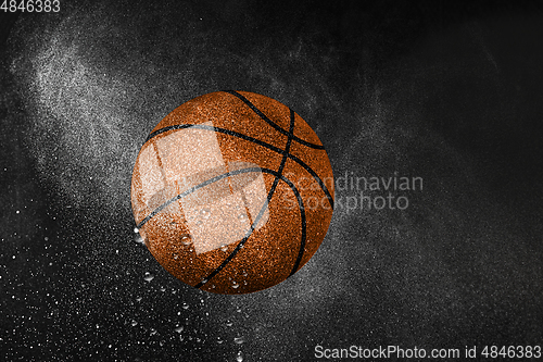 Image of Basketball ball flying in water drops and splashes isolated on black background