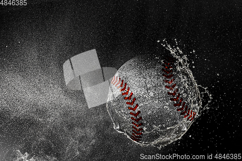 Image of Baseball ball flying in water drops and splashes isolated on black background