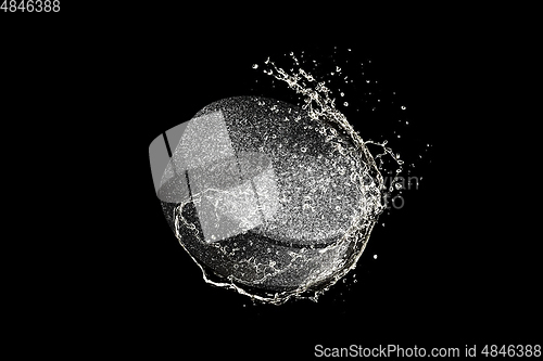 Image of Puck flying in water drops and splashes isolated on black background
