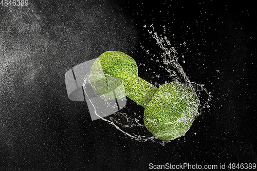 Image of Dumbbell flying in water drops and splashes isolated on black background