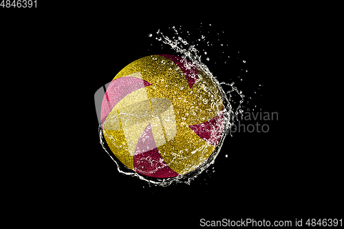 Image of Volleyball ball flying in water drops and splashes isolated on black background