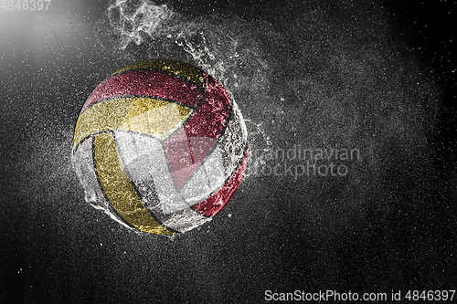 Image of Volleyball ball flying in water drops and splashes isolated on black background