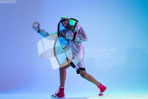 Image of High-fashion styled man in white outfit pacticing box isolted over gradient background in neon light